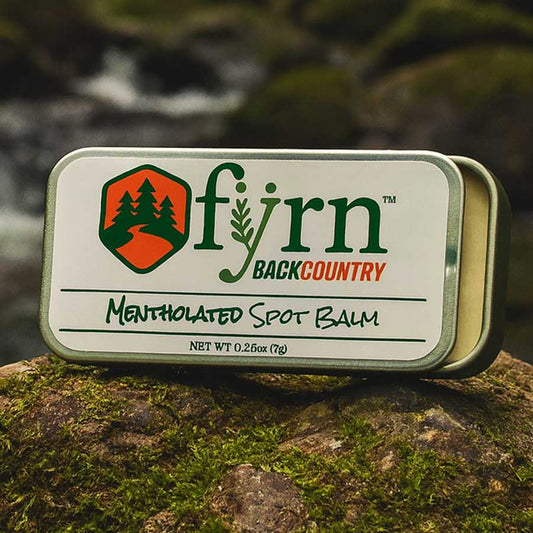 Fyrn Backcountry Mentholated Spot Balm tin on a rock with a natural background