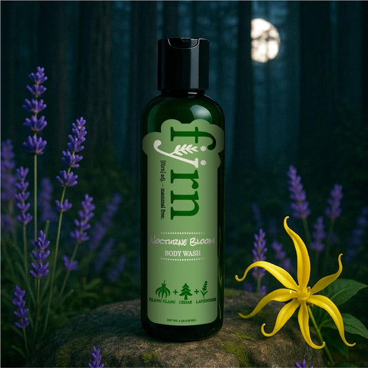 Bottle of 'Firn' body wash with lavender and a yellow flower in a forest setting