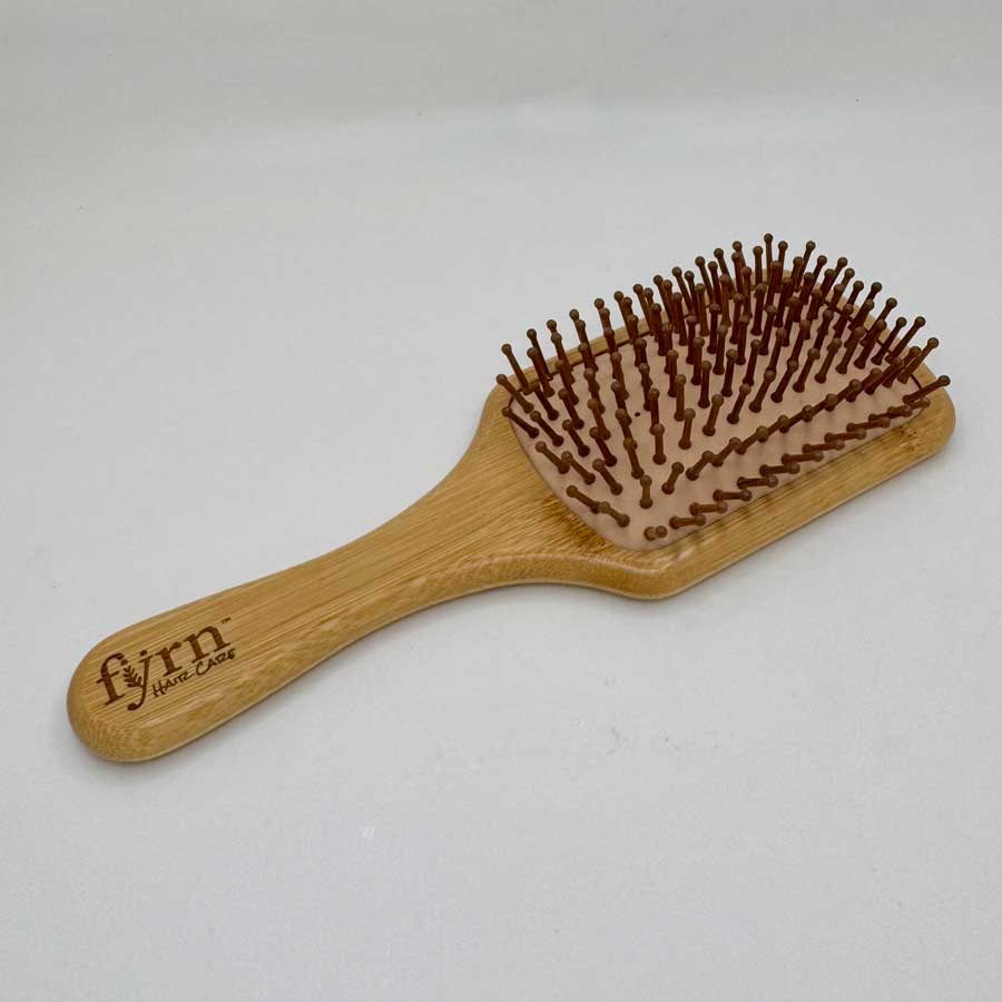 Wooden hairbrush with brown bristles on a white background