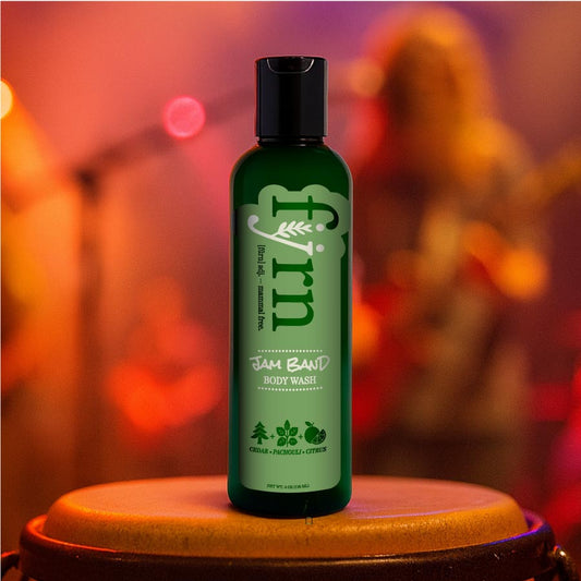 Green bottle of Jam Band body wash on a wooden stand with a blurred colorful background