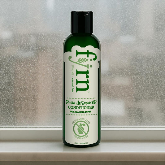 Green bottle of pure unscented conditioner on a windowsill with a blurred background