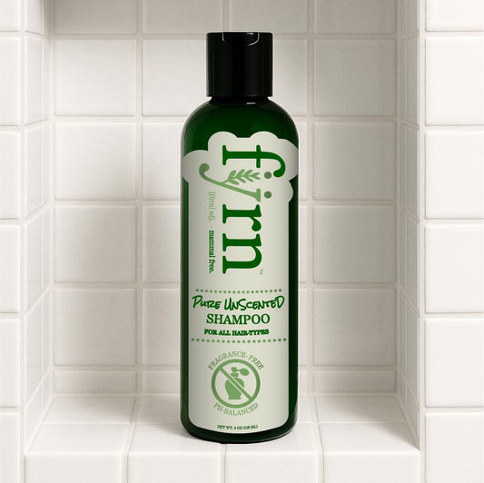 Green shampoo bottle labeled 'fyrn' on a tiled bathroom shelf